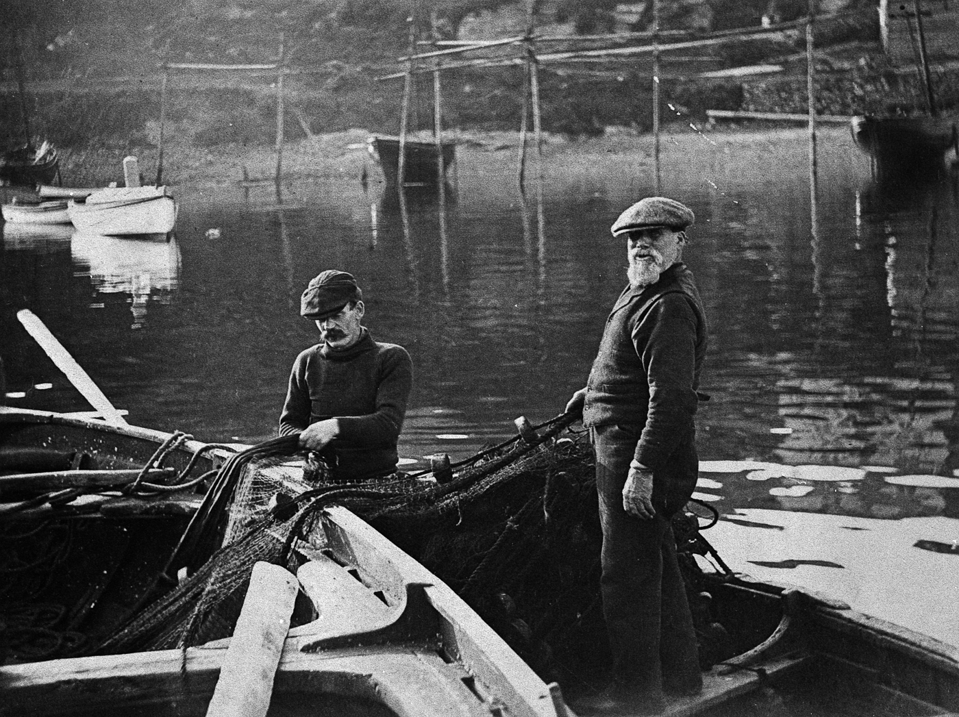 Two men transferring a ringnet into a small boat, Tarbert, 1912.