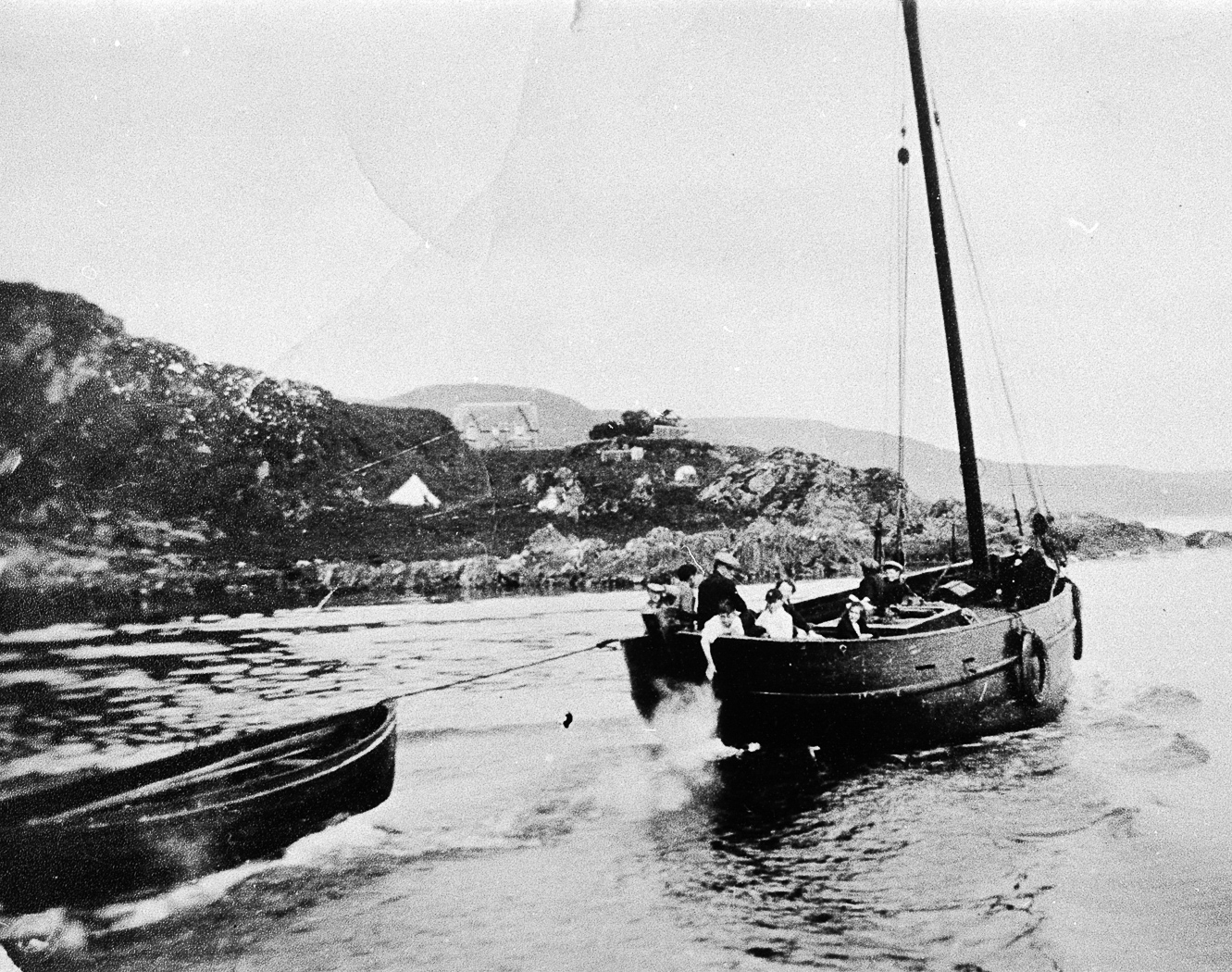 Boat pulling smaller boat out of harbour, Carradale. Engines came into use in the early 1900s. Robert Robertson of Campbeltown installed a 7.9HP Kelving in his 35ft skiff, 'The Brothers'.
