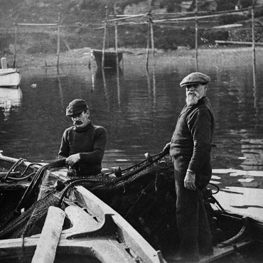 Two men transferring a ringnet into a small boat, Tarbert, 1912.