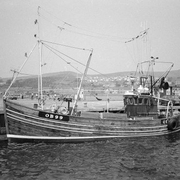 Dual purpose ringnetter and trawler 'Aquila', OB99, in harbour, Campbeltown, 1983. 'Acquila', OB99, was built in Girvan in 1972. She had a varnished hull, light blue steelwork, and a varnished wheelhuse. She was later rigged out for pair trawling and in February 1986, she was sold to Pittenweem.